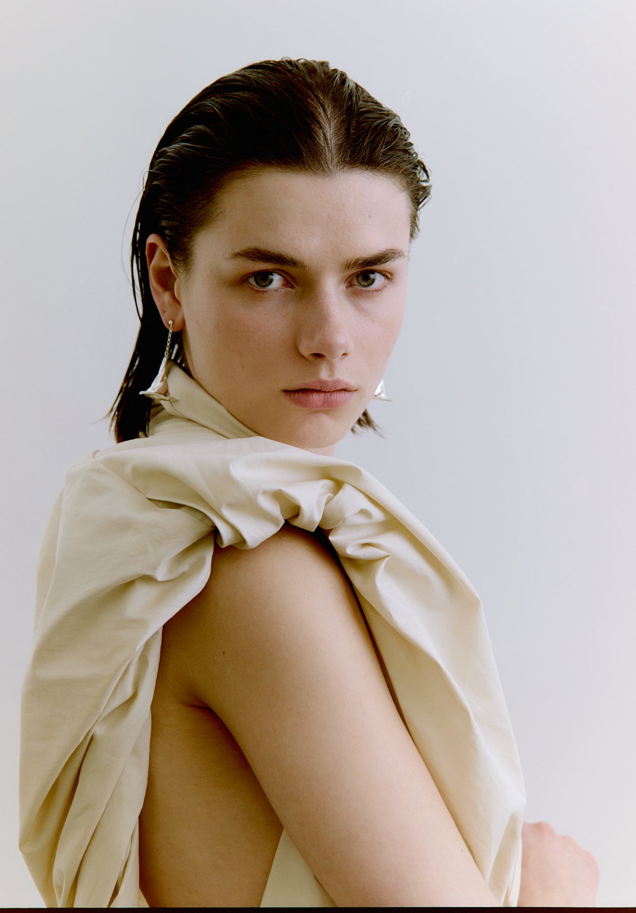 Woman wearing silver earrings against a plain background