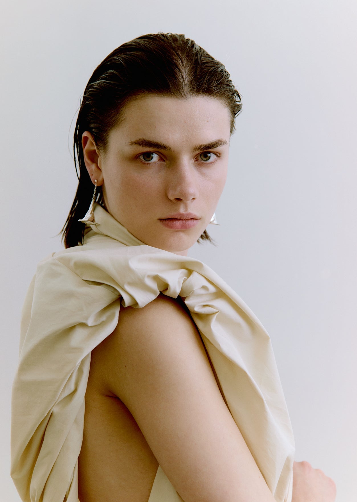 Woman wearing silver earrings against a plain background