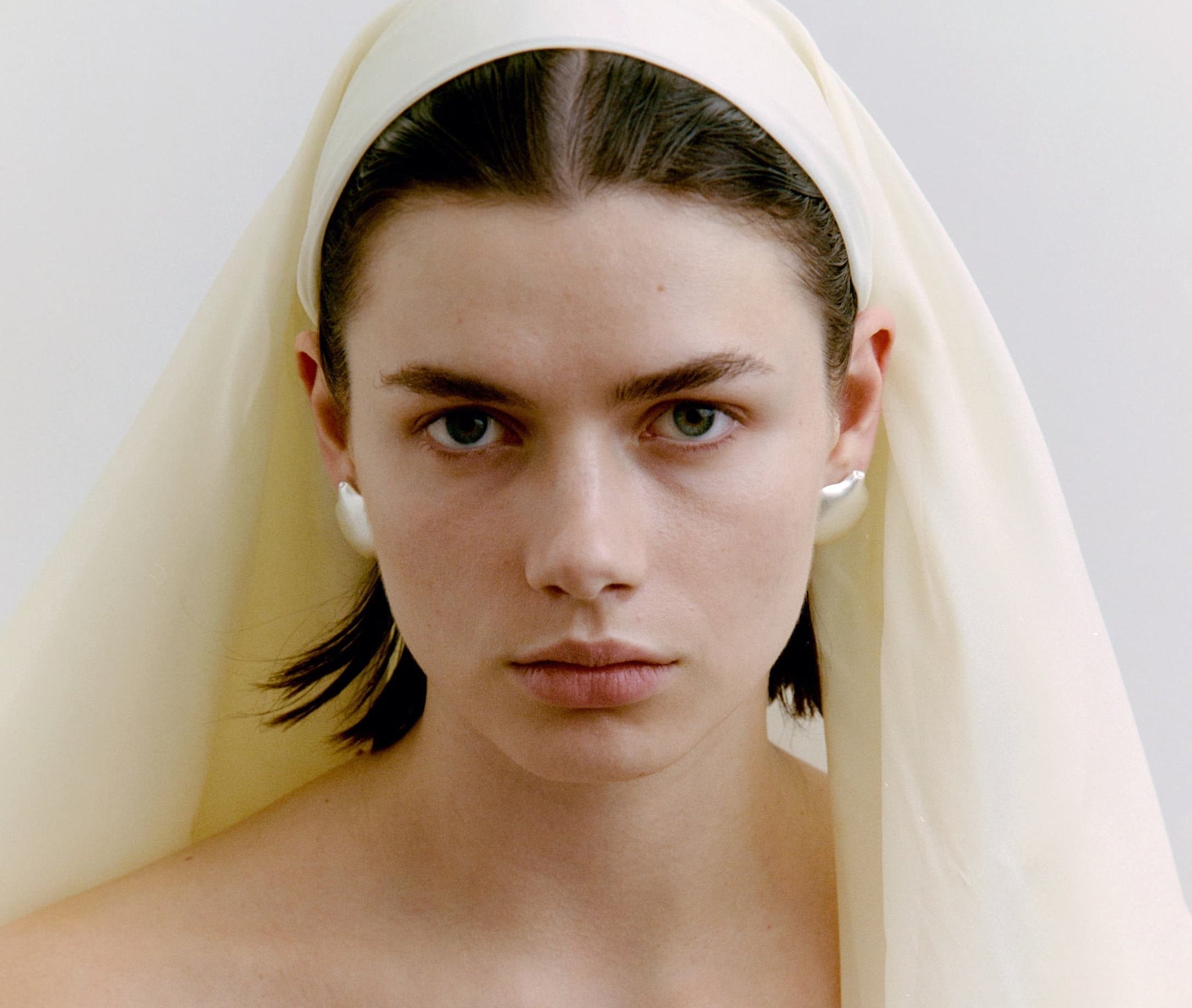 WOman wearing silver earrings and a head scarf.