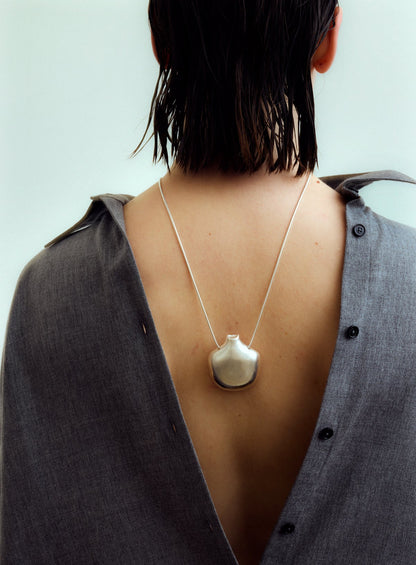 Person wearing a necklace with a pendant, back view