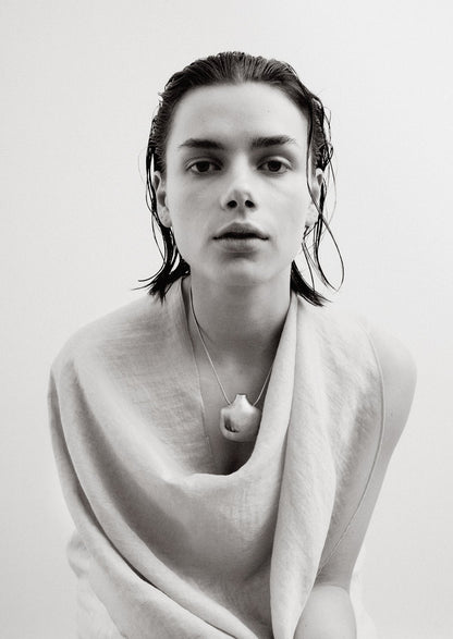 Black and white portrait of a person with wet hair wearing a light scarf and necklace.