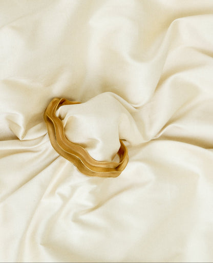 Gold bracelet on a beige fabric background