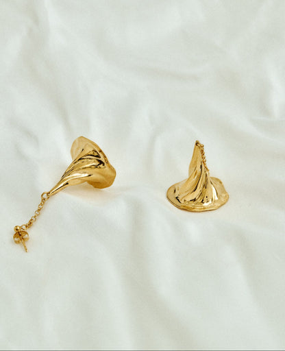 Gold earrings on a white fabric background