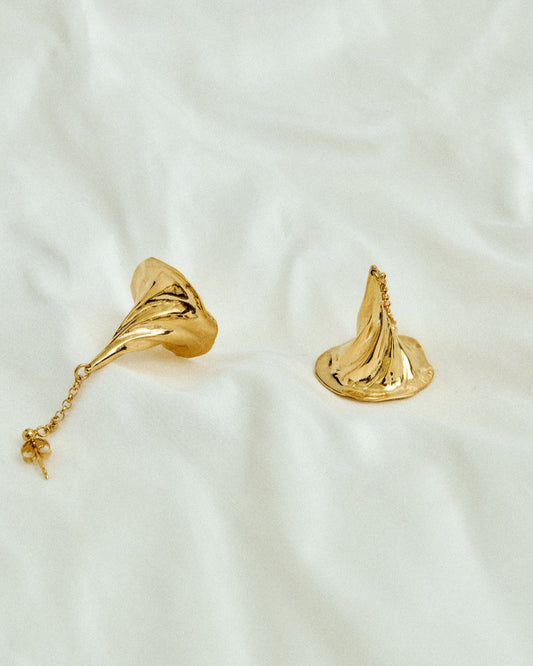Gold earrings on a white fabric background