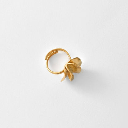 A gold-toned adjustable ring with a sculpted, organic leaf-like protrusion on one side, photographed on a clean white background.