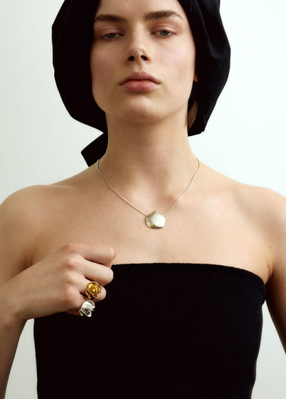 Woman wearing a black strapless top and headscarf, wearing silver and gold jewelry