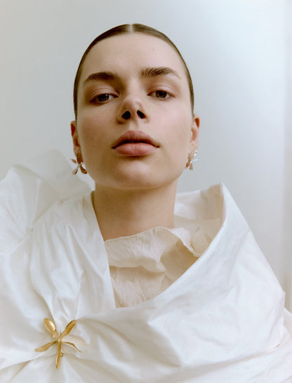 Woman wearing gold jewelry against a plain background
