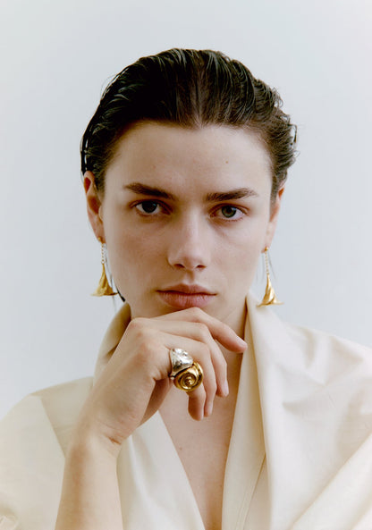 Person wearing gold jewelry against a plain background