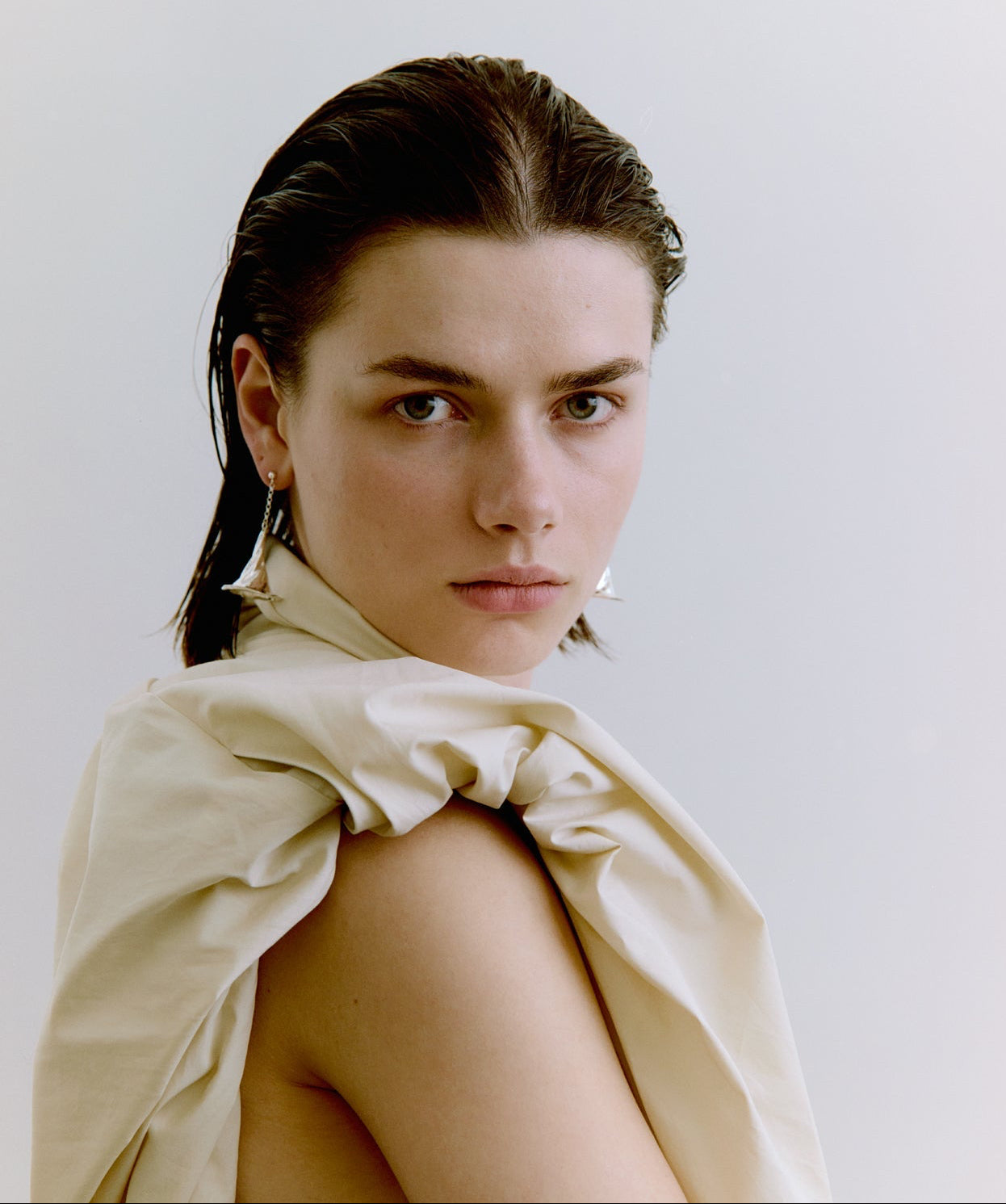 Woman wearing silver earrings against a plain background