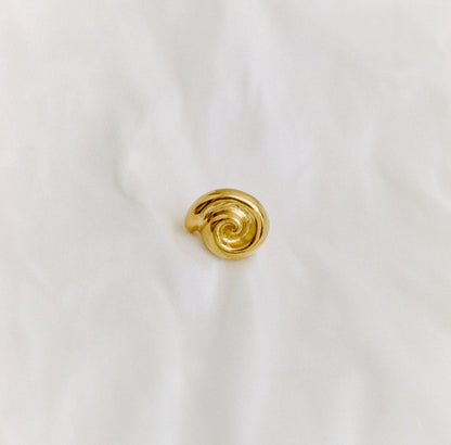 Gold spiral ring on a white fabric background