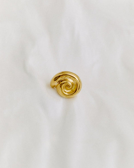 Gold spiral ring on a white fabric background