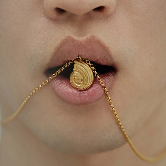 Gold necklace between the lips of a model