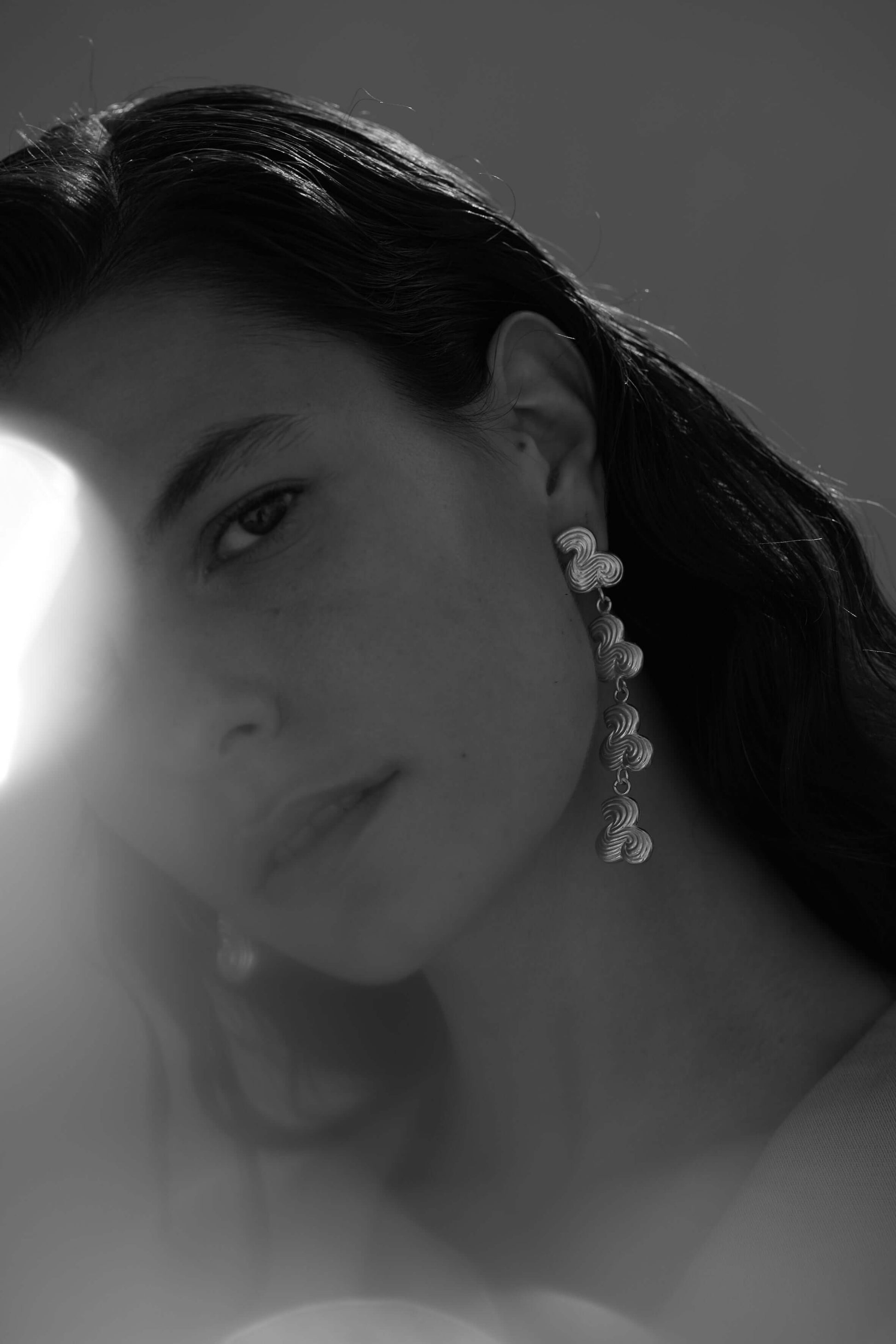 Female model wearing drop earring in silver