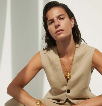 Female model sitting, wearing gold jewelry