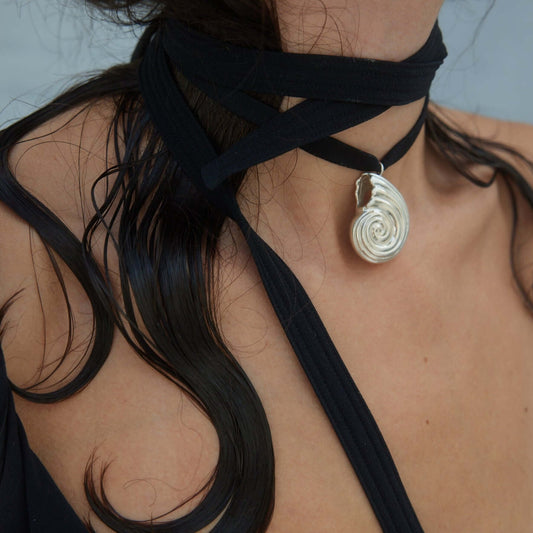 Models neck wearing silver necklace with silk ribbon
