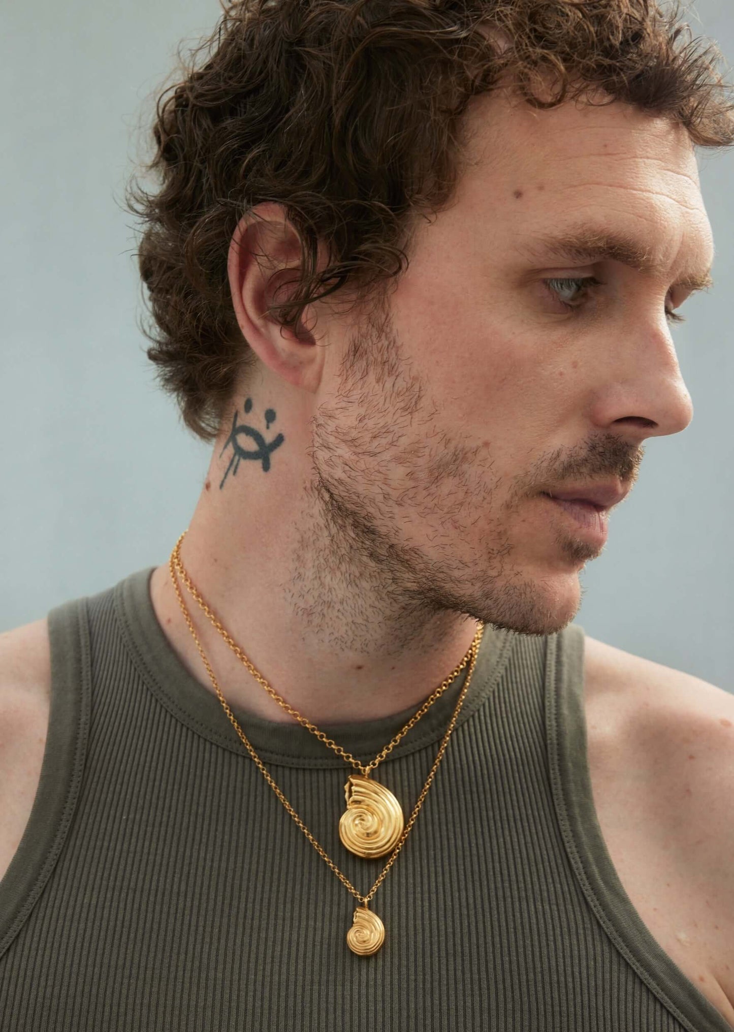 Male model with neck tattoo and gold necklaces
