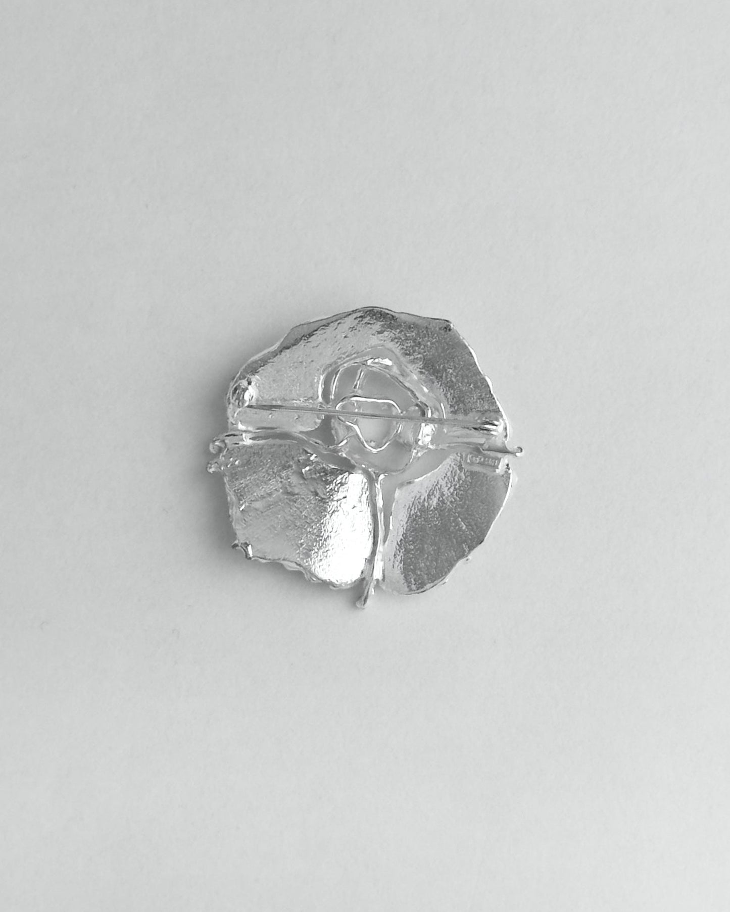 Silver brooch on a light gray background