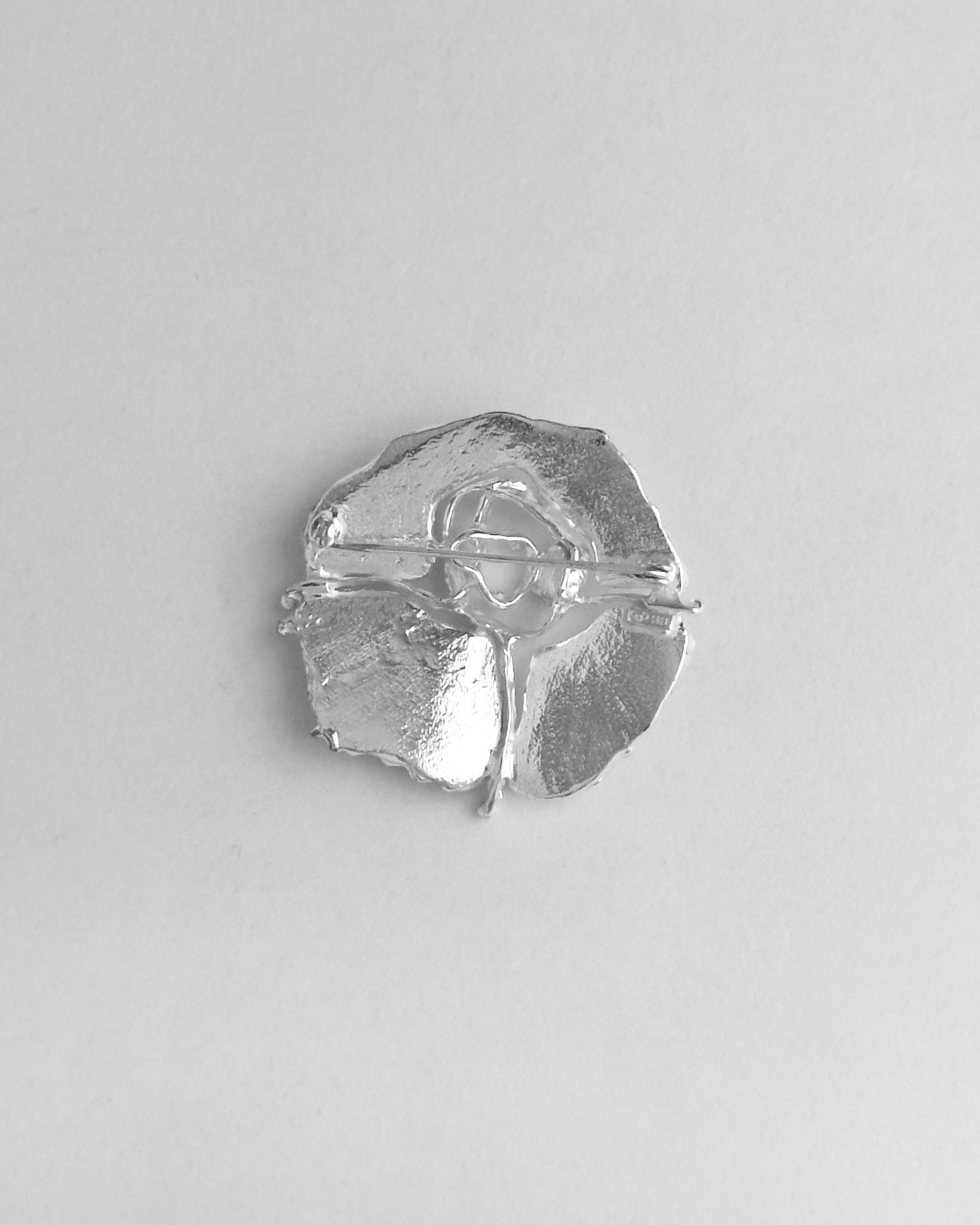 Silver brooch on a light gray background
