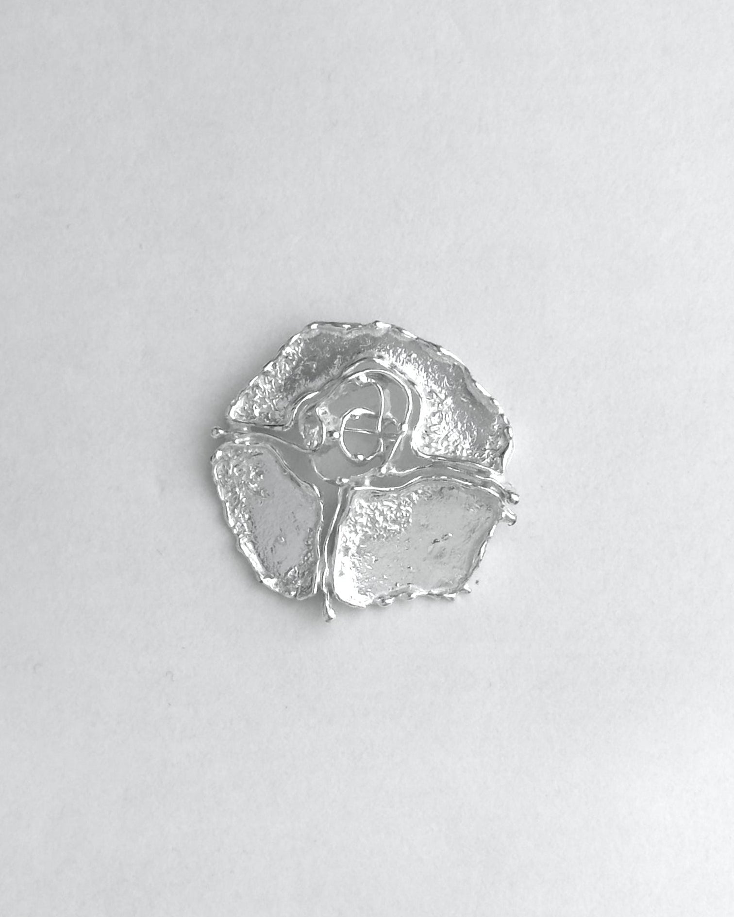 Silver brooch on a light gray background