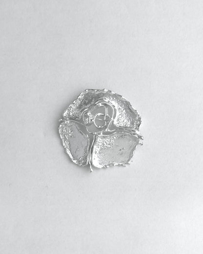 Silver brooch on a light gray background
