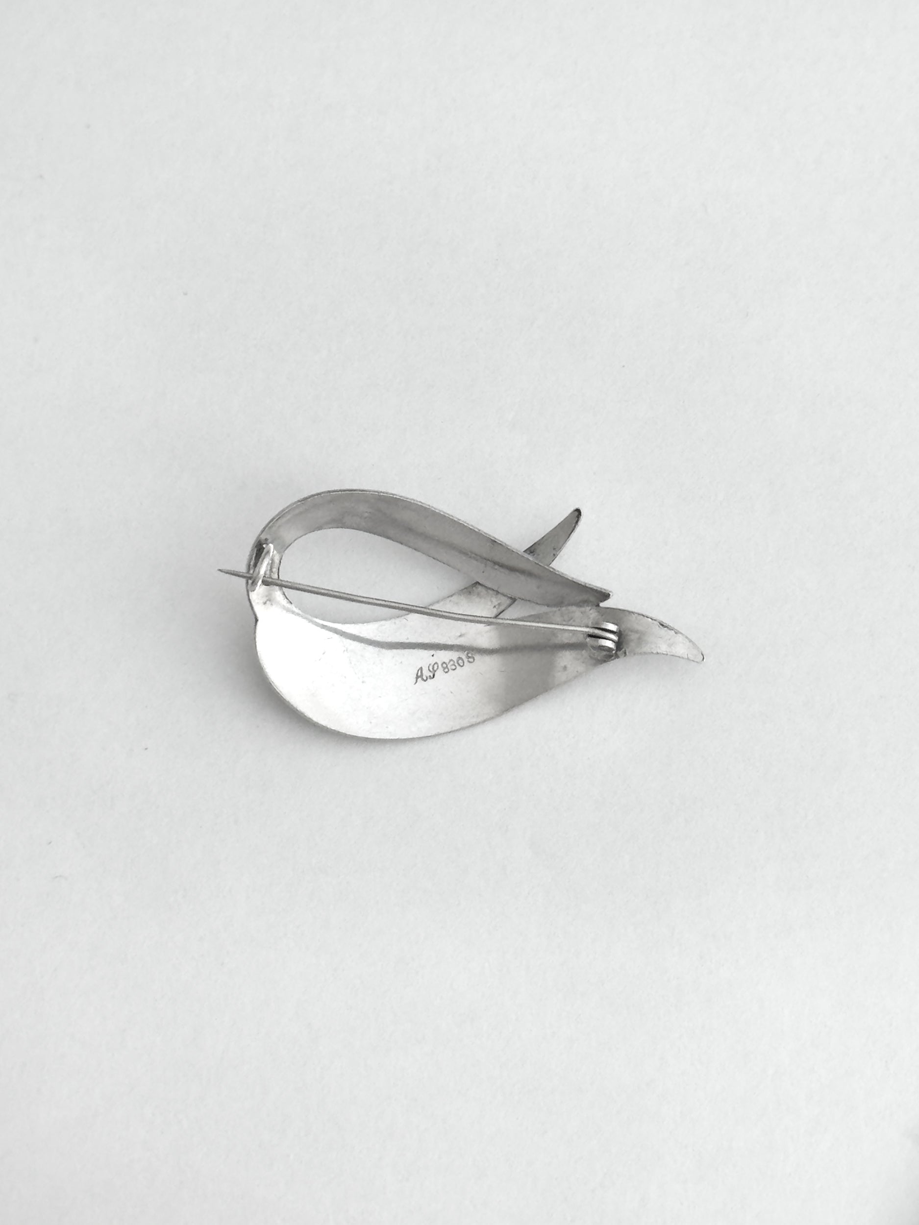 Silver brooche on a light gray background