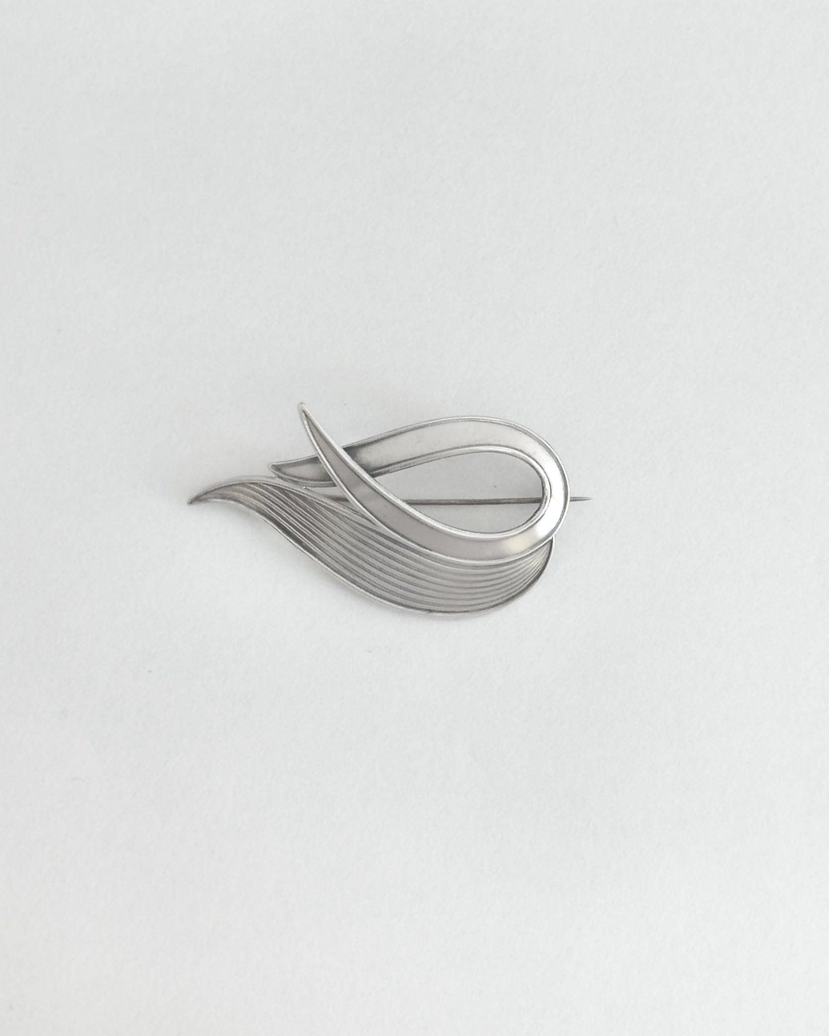 Silver brooch on a light gray background