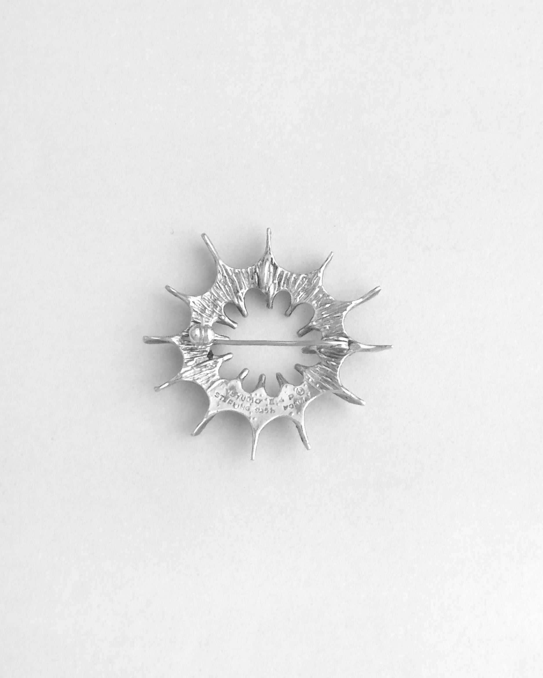 Silver star-shaped brooch on a white background