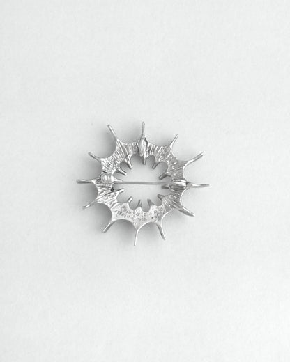 Silver star-shaped brooch on a white background