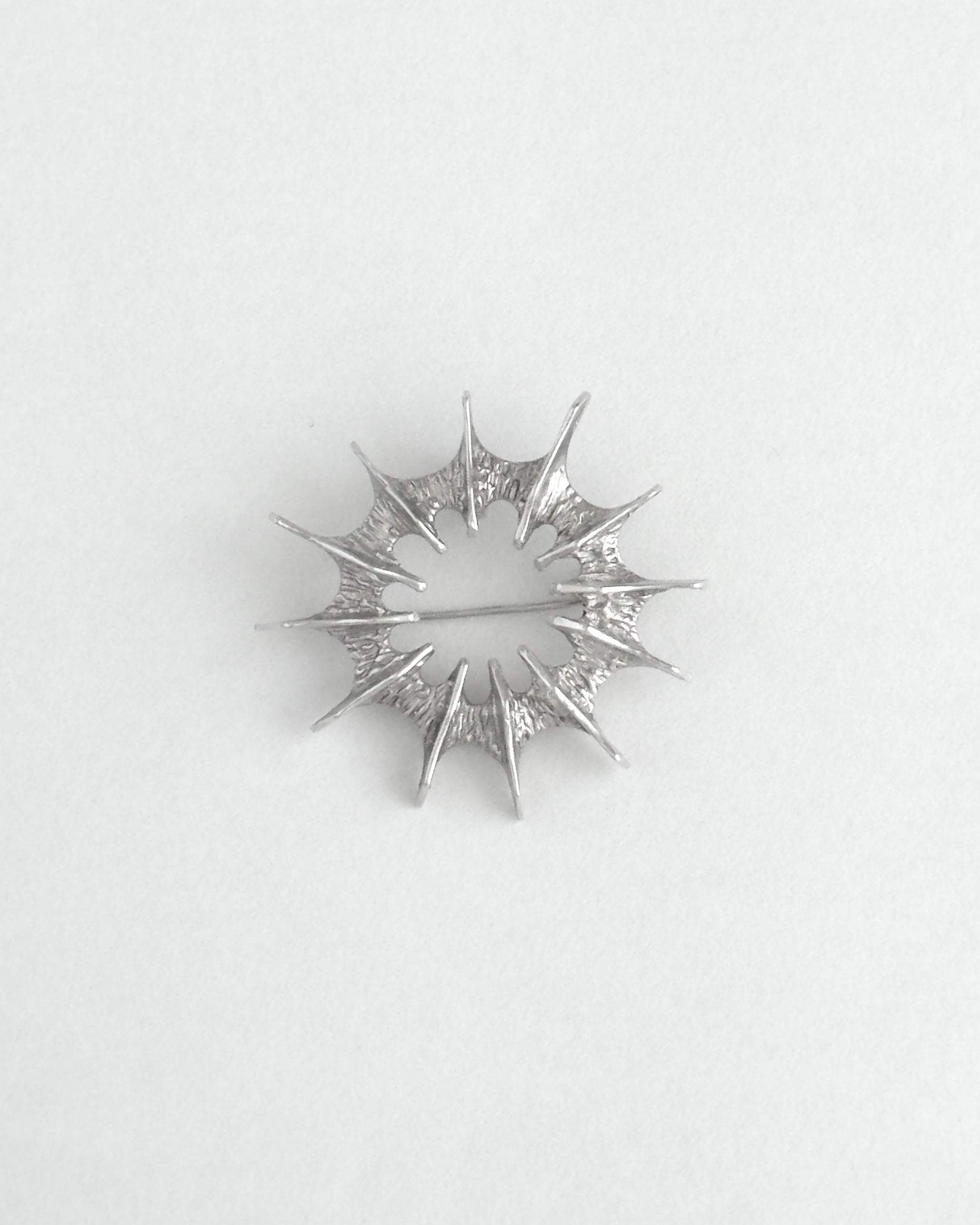 Silver star-shaped brooch on a light gray background