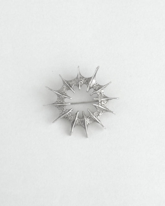 Silver star-shaped brooch on a light gray background