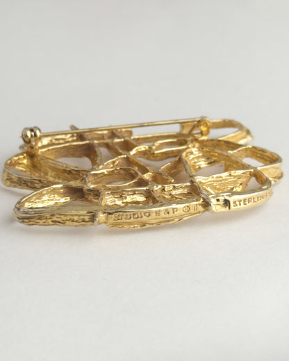 Gold brooch with engraved text on a light gray background