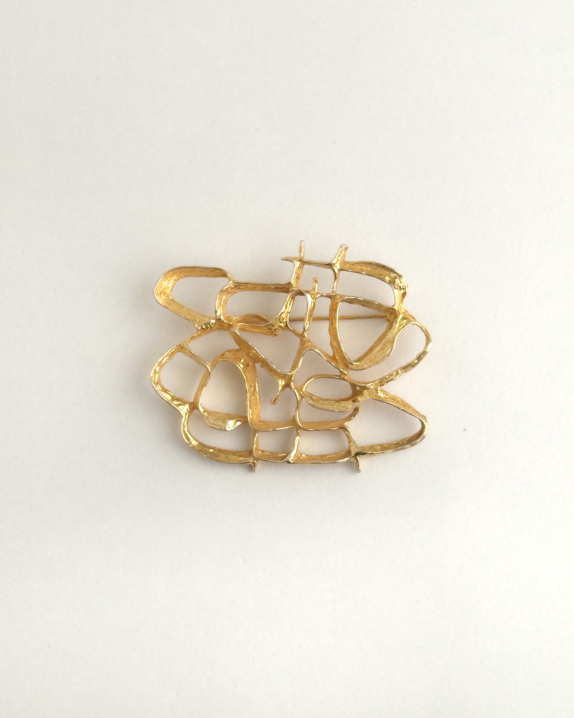 Gold brooch on a light gray background