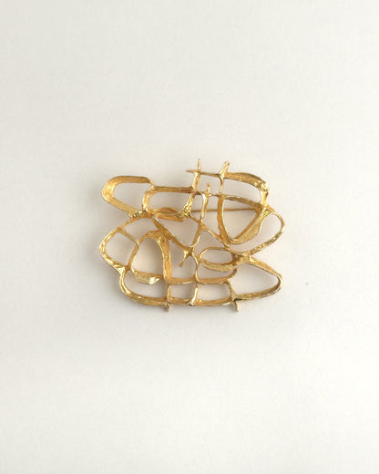 Gold brooch on a light gray background