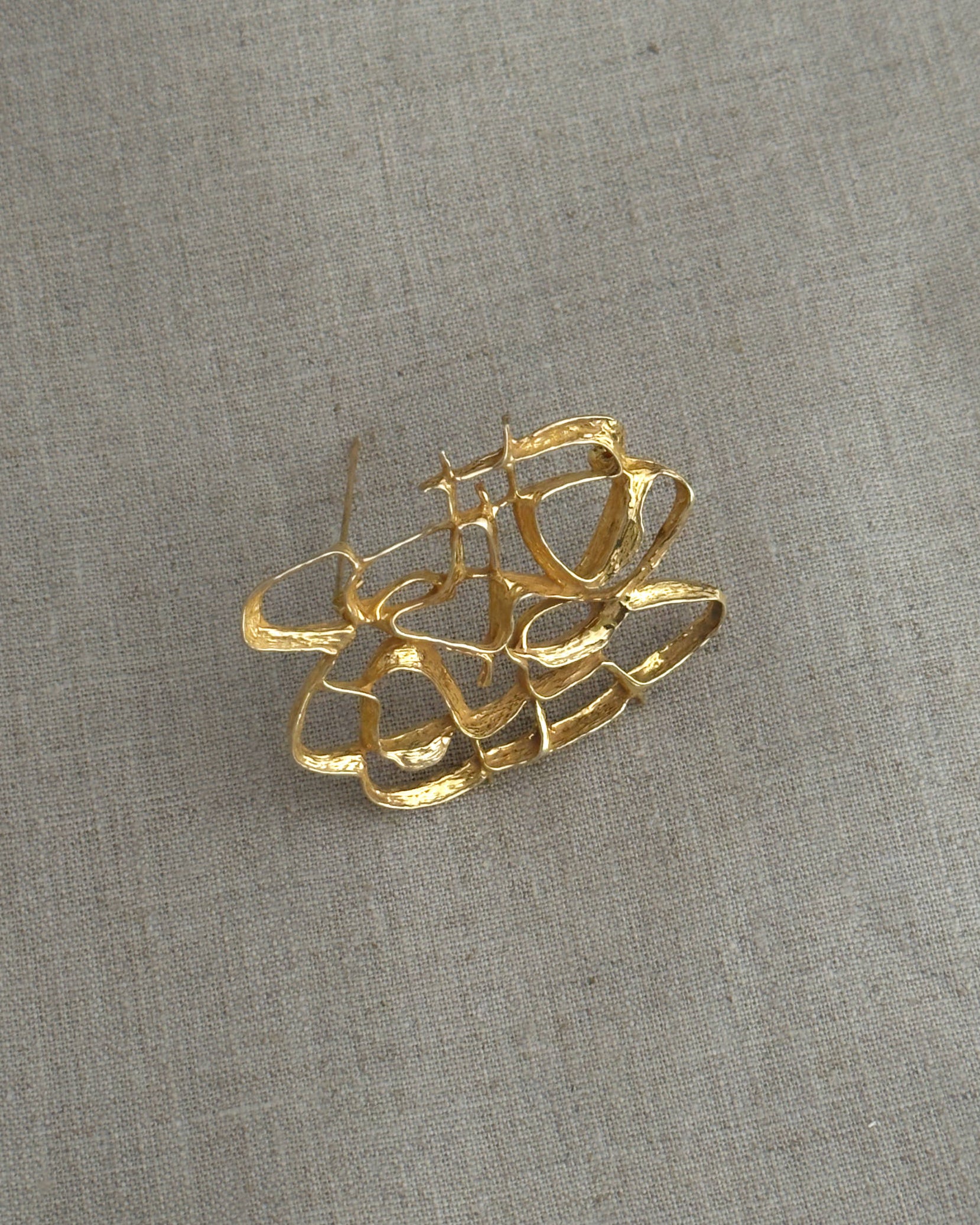 Gold brooch on a textured gray background
