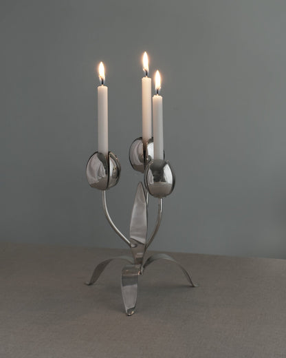 Silver candelabra with three lit candles on a gray background