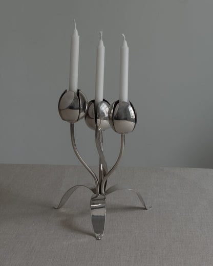 Silver candelabra with three white candles on a gray surface and background