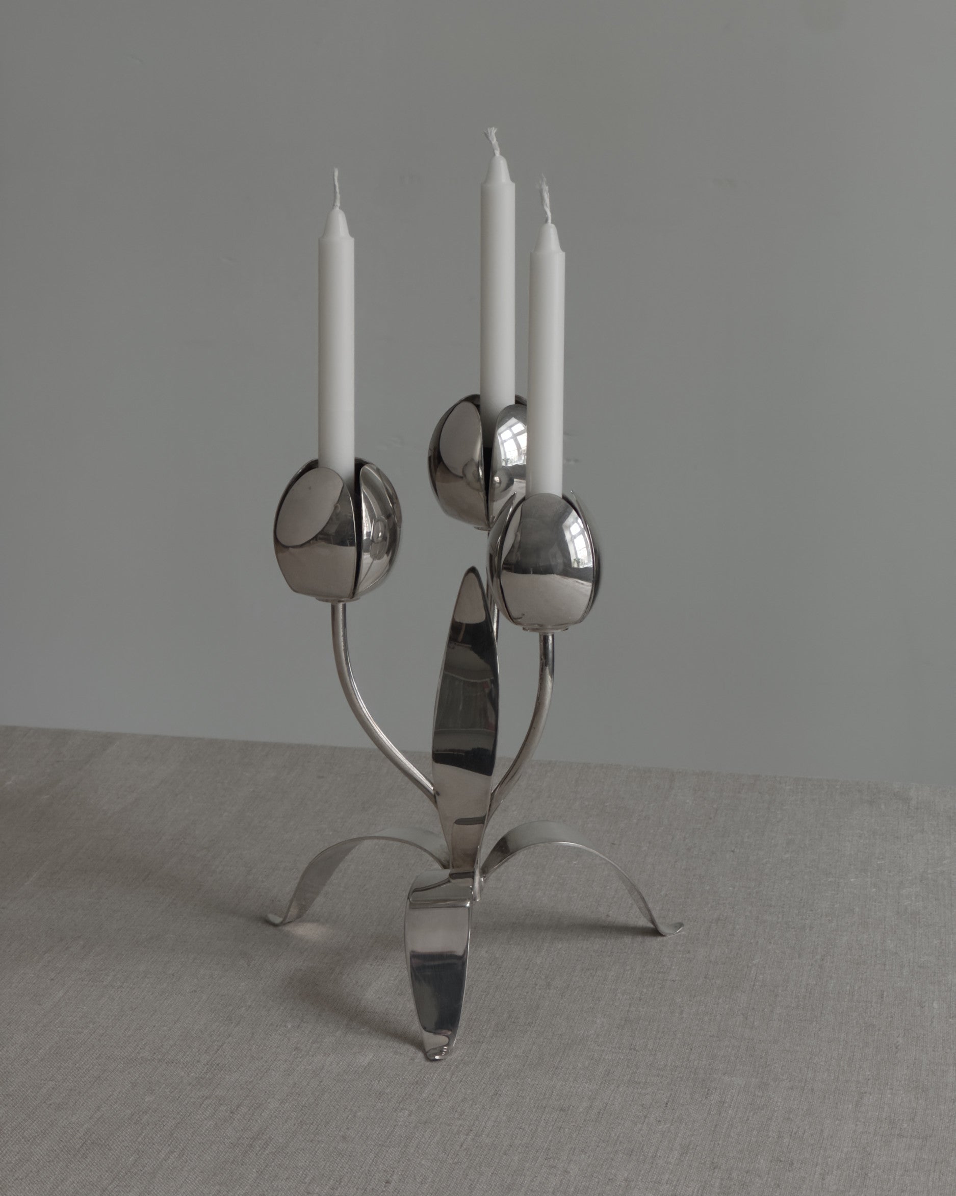 Silver candelabra with three candles on a gray background