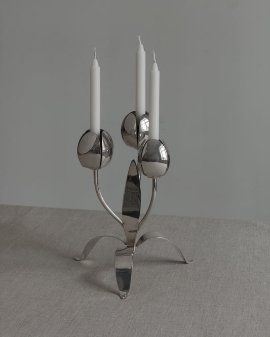 Silver candelabra with three candles on a gray background