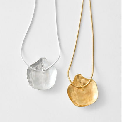Gold necklace and silver necklace with a round pendant on a light gray background