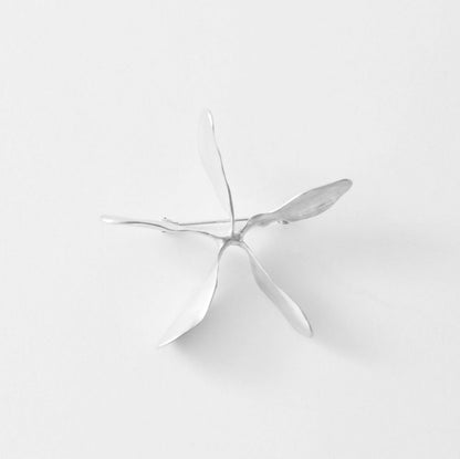 Silver brooche on a light gray background