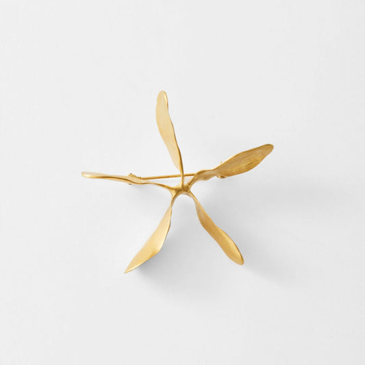 Gold brooch on a light gray background