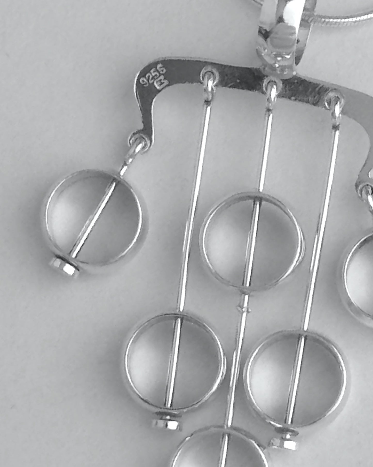 Silver necklace with a unique pendant on a light gray background