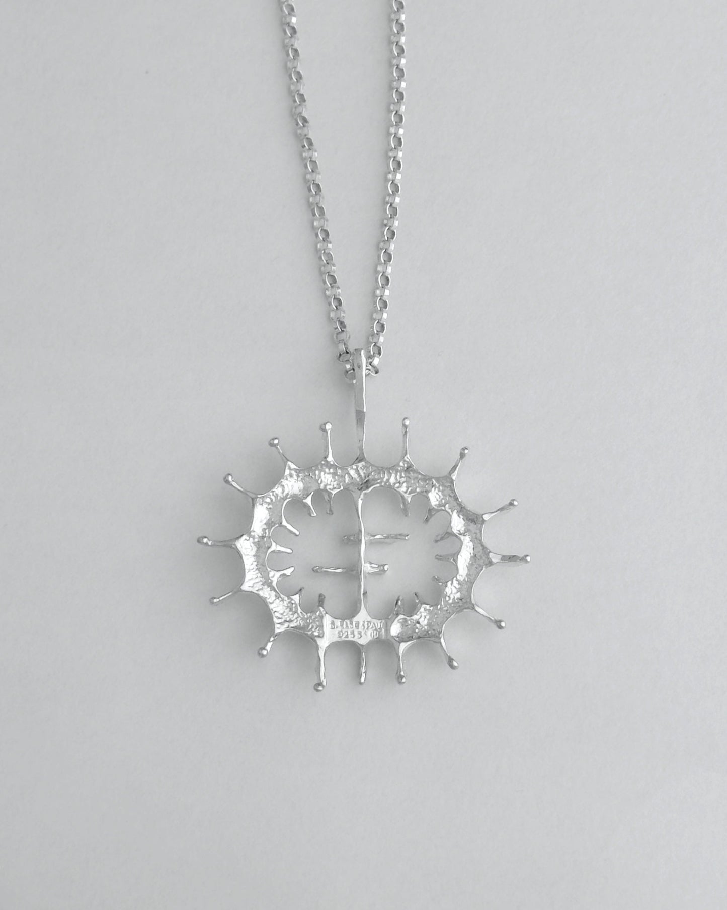 Silver necklace with a unique pendant on a light gray background
