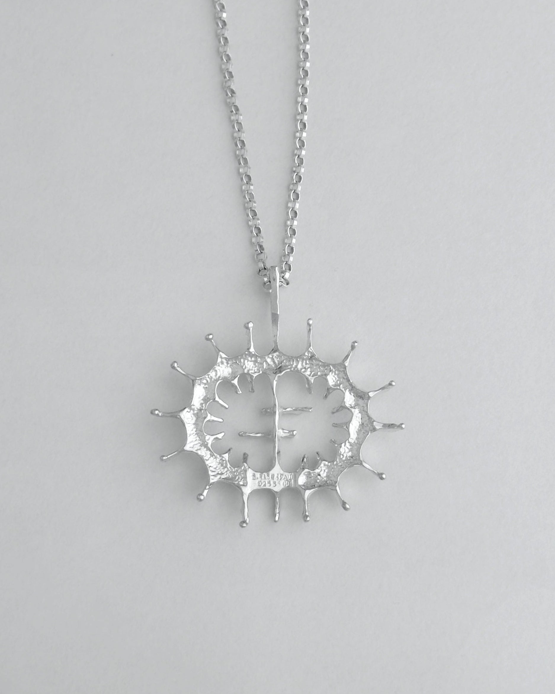 Silver necklace with a unique pendant on a light gray background