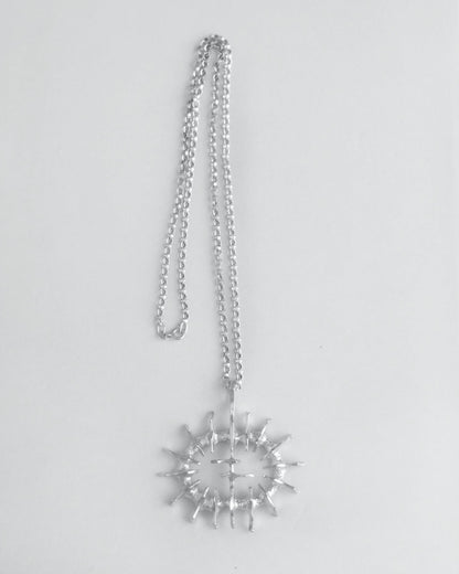 Silver necklace with a large sculptural pendant on a light gray background