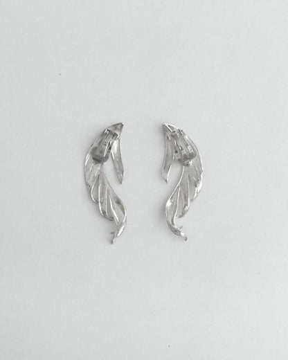 Pair of silver leaf-shaped earrings on a light gray background