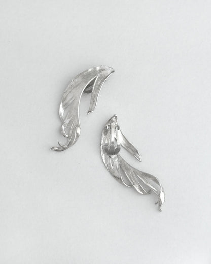 Silver leaf-shaped earrings on a light gray background