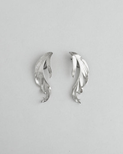 Pair of silver leaf-shaped earrings on a light gray background