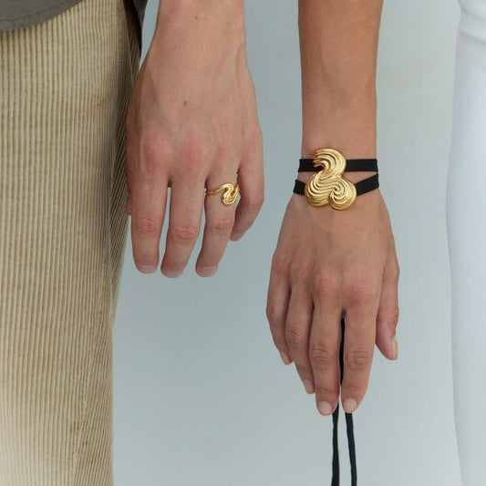 Two persons hands wearing gold jewelry