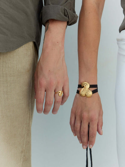 Two persons hands wearing gold jewelry